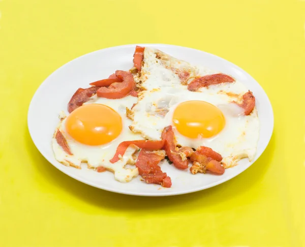 Gebakken eieren met tomaten op geel — Stockfoto