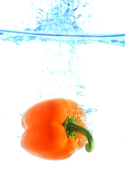 Orange pepper falling in water — Stock Photo, Image