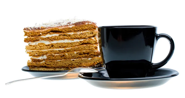 Black cup and piece of honey cake — Stock Photo, Image