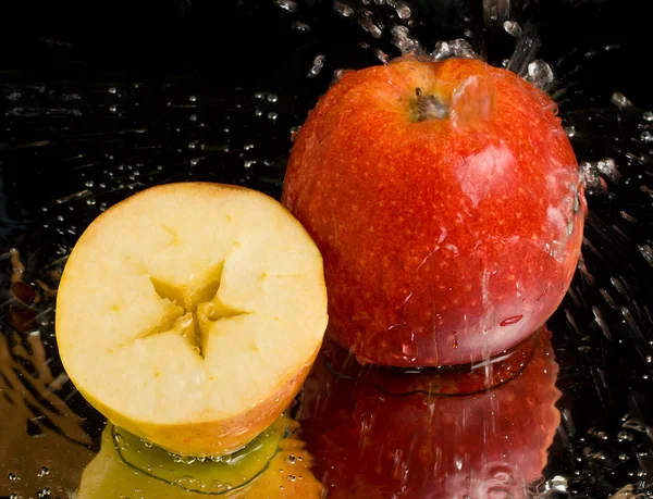 Full apple and half with water splashing — ストック写真