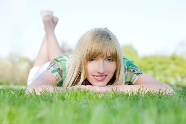 Улыбающаяся женщина, лежащая на траве — стоковое фото