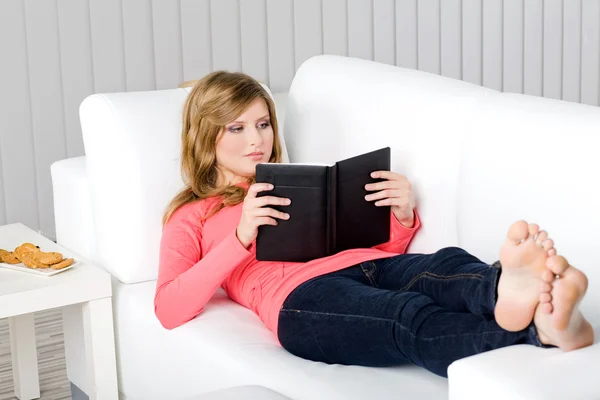 Jovem mulher no sofá leitura — Fotografia de Stock