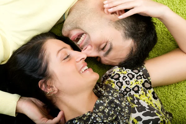 Jovem casal feliz que coloca no tapete — Fotografia de Stock