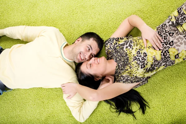 年轻快乐的夫妻躺在地毯上 — 图库照片