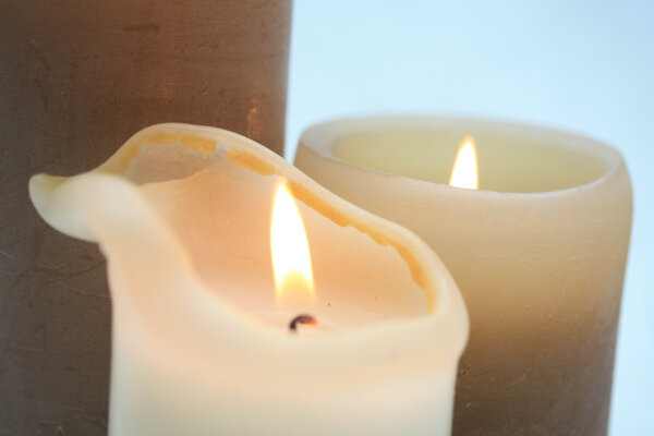 Close up of two burning candles in beige and ivory white