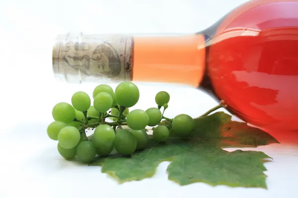 Uvas e garrafa de vinho rosa — Fotografia de Stock