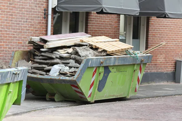 Müllcontainer nahe Baustelle beladen lizenzfreie Stockbilder
