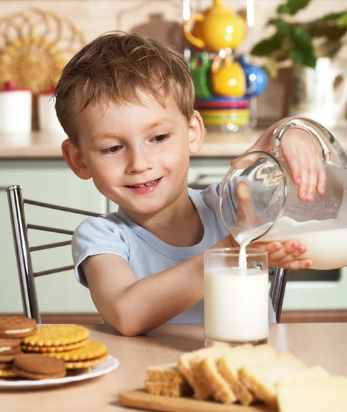 Criança feliz derrama leite de jarro — Fotografia de Stock