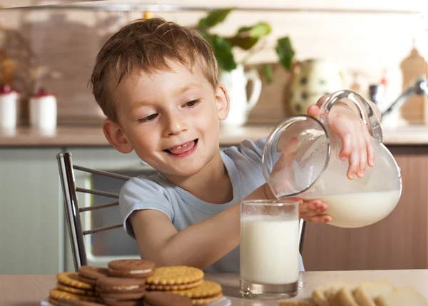 Il bambino sano versa il latte dalla brocca Foto Stock Royalty Free