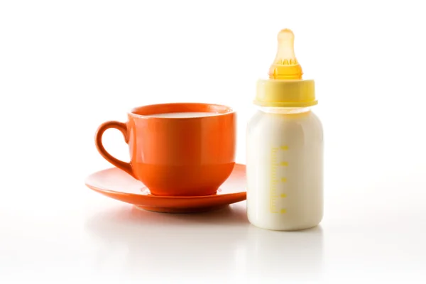 Cup with milk and a bottle — Stock Photo, Image