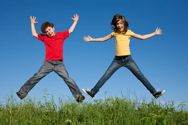 Dzieci, skoki, działa przeciw błękitne niebo — Zdjęcie stockowe