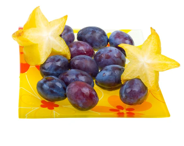 Carambole et prunes sur une assiette sur blanc — Photo