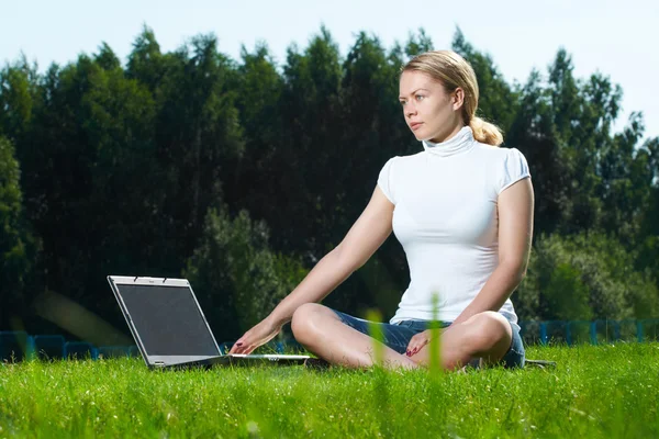 A menina com laptop em um gramado verde — Fotografia de Stock
