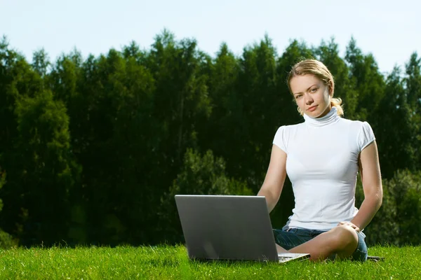Дівчина з ноутбуком на зеленому газоні — стокове фото