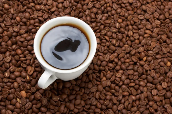 Kubek z kawą, kosztuje na ziarna kawy — Zdjęcie stockowe