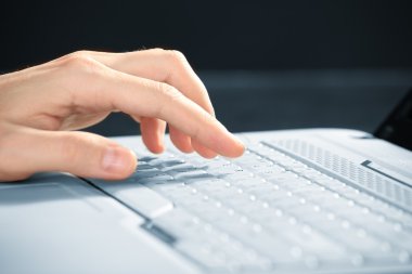 Erkek eller dizüstü bilgisayarda yazıyor.