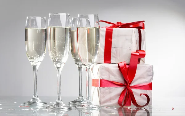 Sklenice šampaňského, dárky s pásky — Stock fotografie