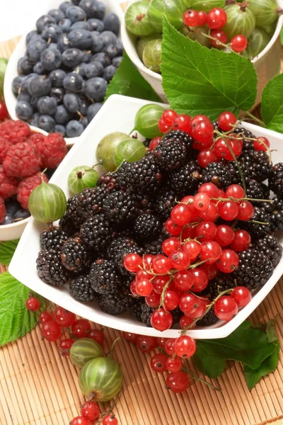 Berries in plates, among green leaves — Stock Photo, Image