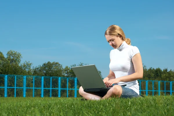 緑の芝生の上のラップトップを持つ少女 — ストック写真