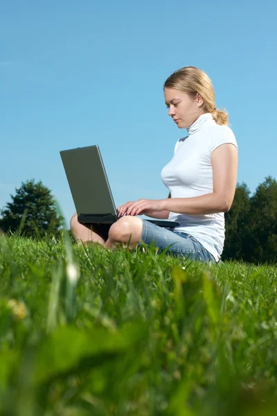 与绿色的草坪上的笔记本电脑女孩 — 图库照片