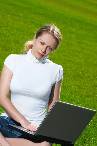 La muchacha con el portátil sobre el césped verde —  Fotos de Stock