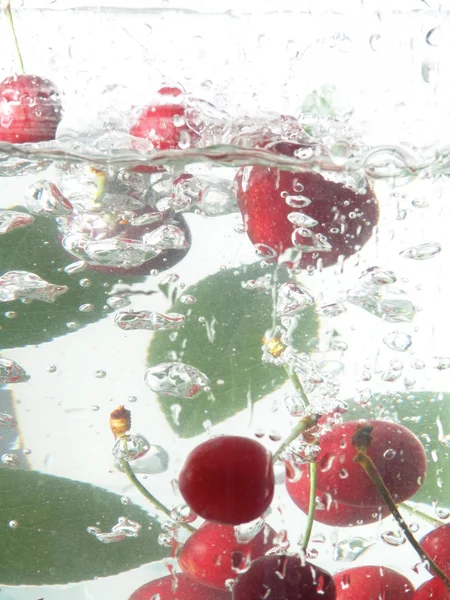 Cerejas caindo na água — Fotografia de Stock