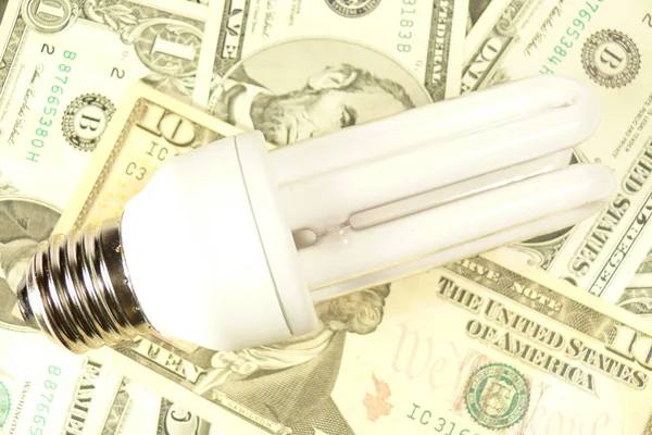 Эко-лампочка и доллары — стоковое фото
