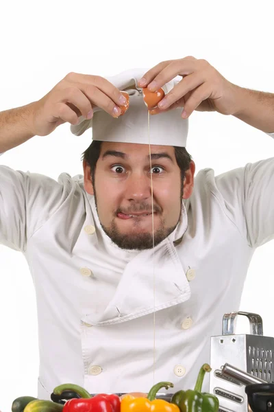 Mladí legrační šéfkuchař popraskání vajíčko — Stock fotografie