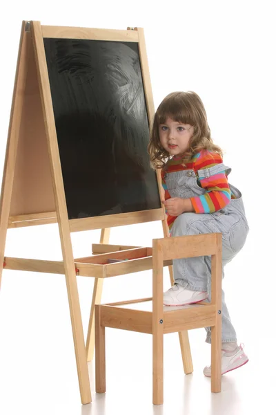 Маленькая девочка забирается на стул — стоковое фото