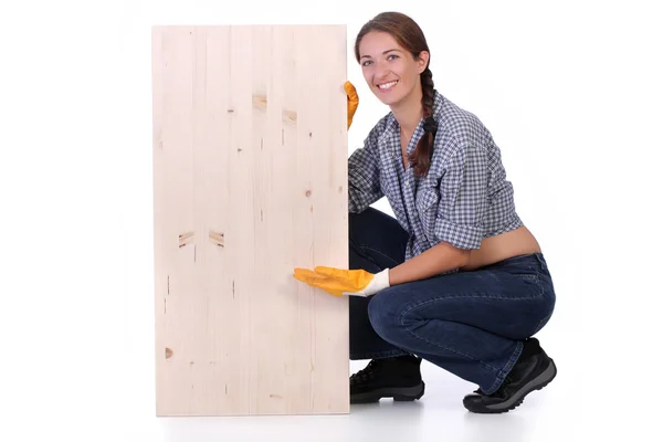 Žena carpenter drží dřevěné prkno — Stock fotografie