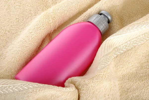 Розовая бутылка с полотенцем — стоковое фото