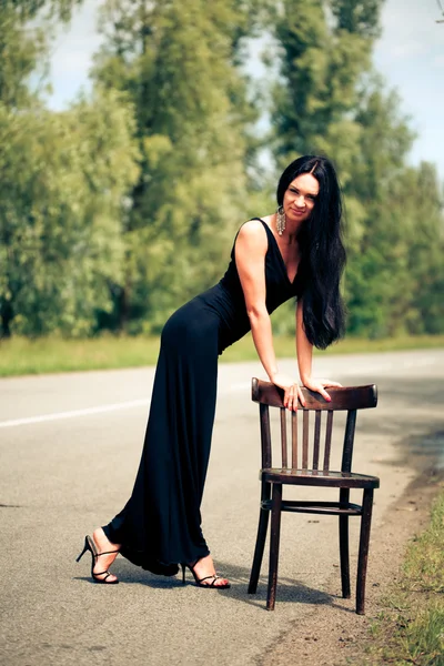 Женщина со стулом на дороге — стоковое фото