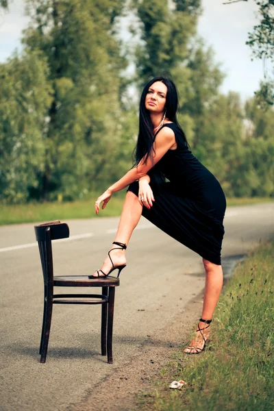 Woman with chair on the road — Stock Photo, Image