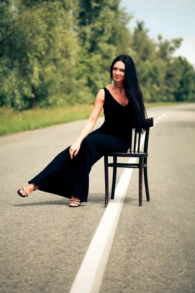 Vrouw zit op een stoel op de weg — Stockfoto