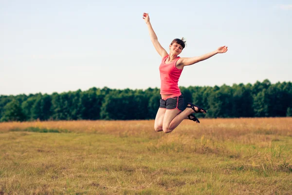 Mujer feliz saltando en el campo amarillo — Foto de Stock