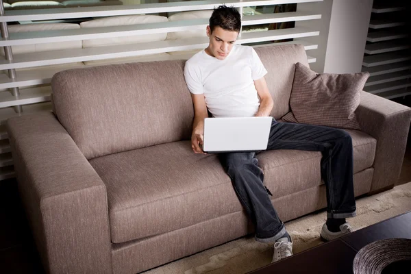 Młody człowiek pracujący na laptopie w domu — Zdjęcie stockowe