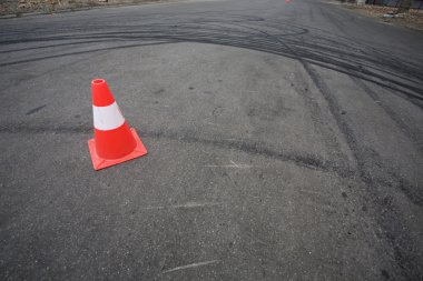 Orange traffic cone and skid marks clipart