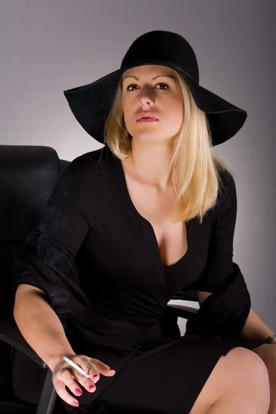 Glamour vrouw in zwarte hoed roken — Stockfoto