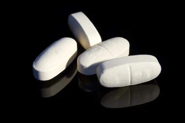 stock image White pills on black with reflection