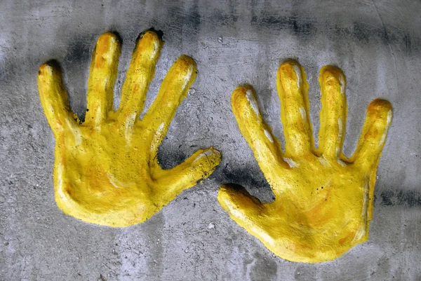 Желтые руки в сером асфальте — стоковое фото