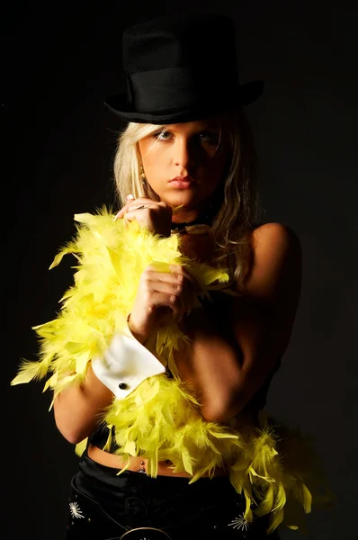 Pretty blonde women on black background wearing hat and yellow feathers — Stock fotografie