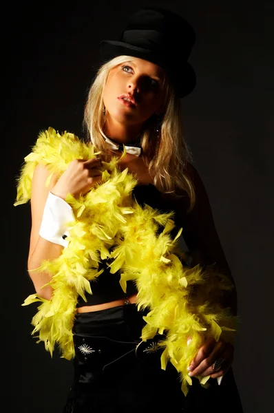 Pretty blonde women on black background wearing hat and yellow feathers — Stock fotografie