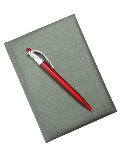 Červené pero na tmavé notebook — Stock fotografie