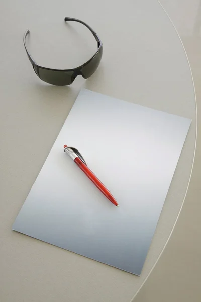Červené pero na šedý notebook — Stock fotografie