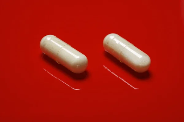 Таблетки на червоному тлі — стокове фото