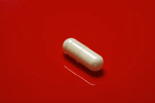 White pills on red background — Stock Photo, Image