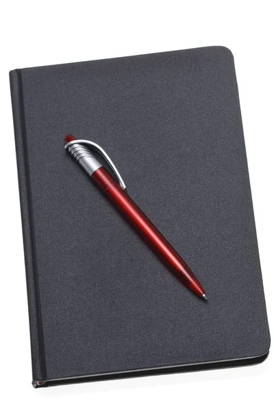 Красная ручка на темном блокноте — стоковое фото