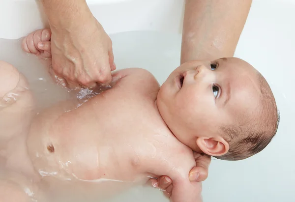 Baby in badkamer, met moeder hand Stockfoto