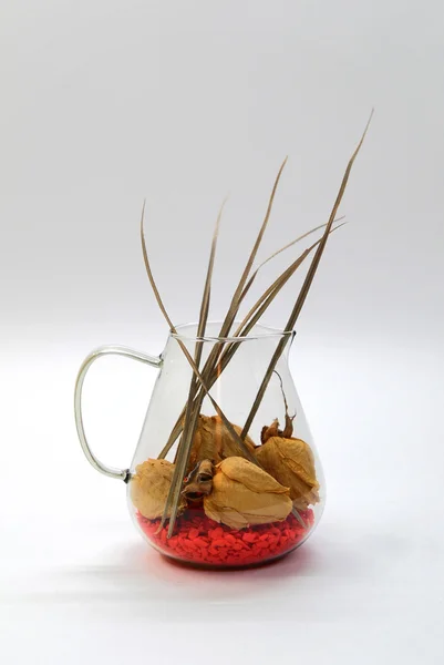 Glazen vaas met droge rozen en rode kiezelsteen — Stockfoto