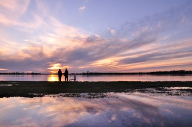 Lovers wi sunrise and beautiful clouds clipart